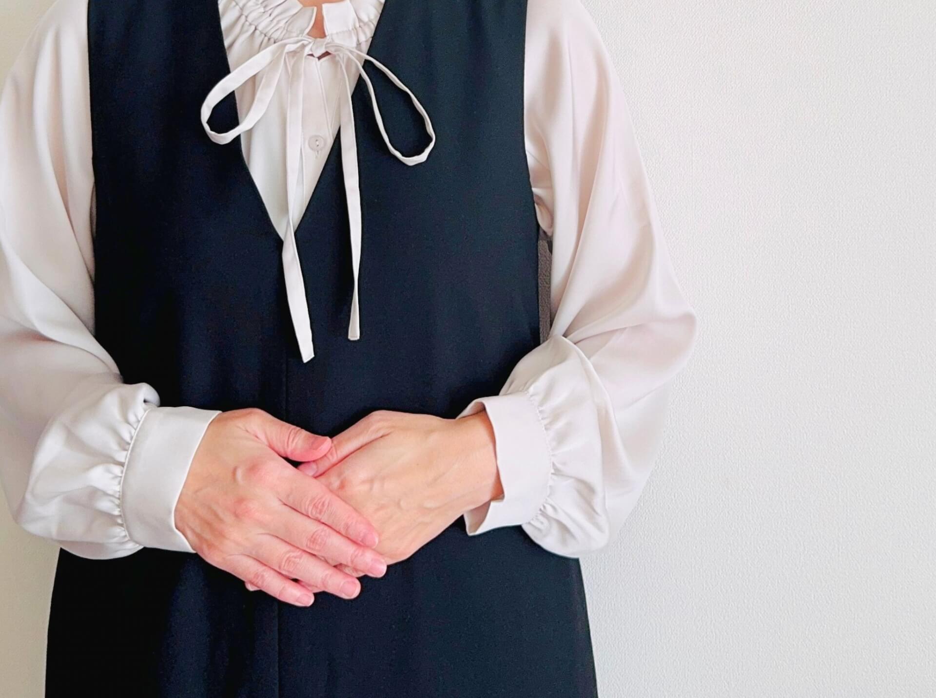 両手を前で組んでいる女性の姿