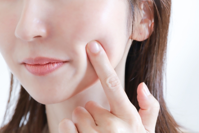 ほほを指で押さえる女性の表情