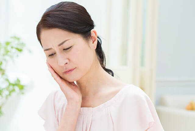 頬に手を当てて考え込む女性